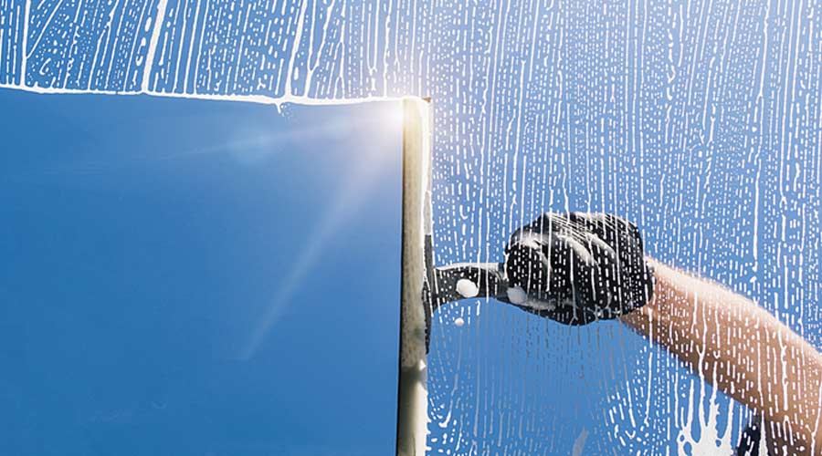 Technician cleaning exterior window with a squeegee